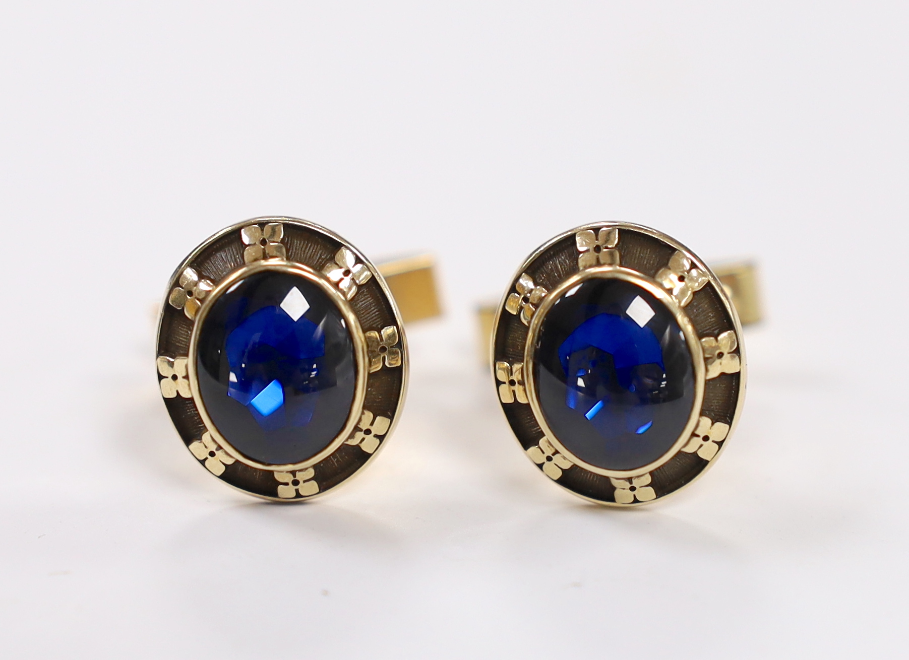 A pair of yellow metal and blue cabochon paste set cufflinks, the backs inscribed 'Jostens 10k', the swivelling arms inscribed '1/20 12k G.F.'.